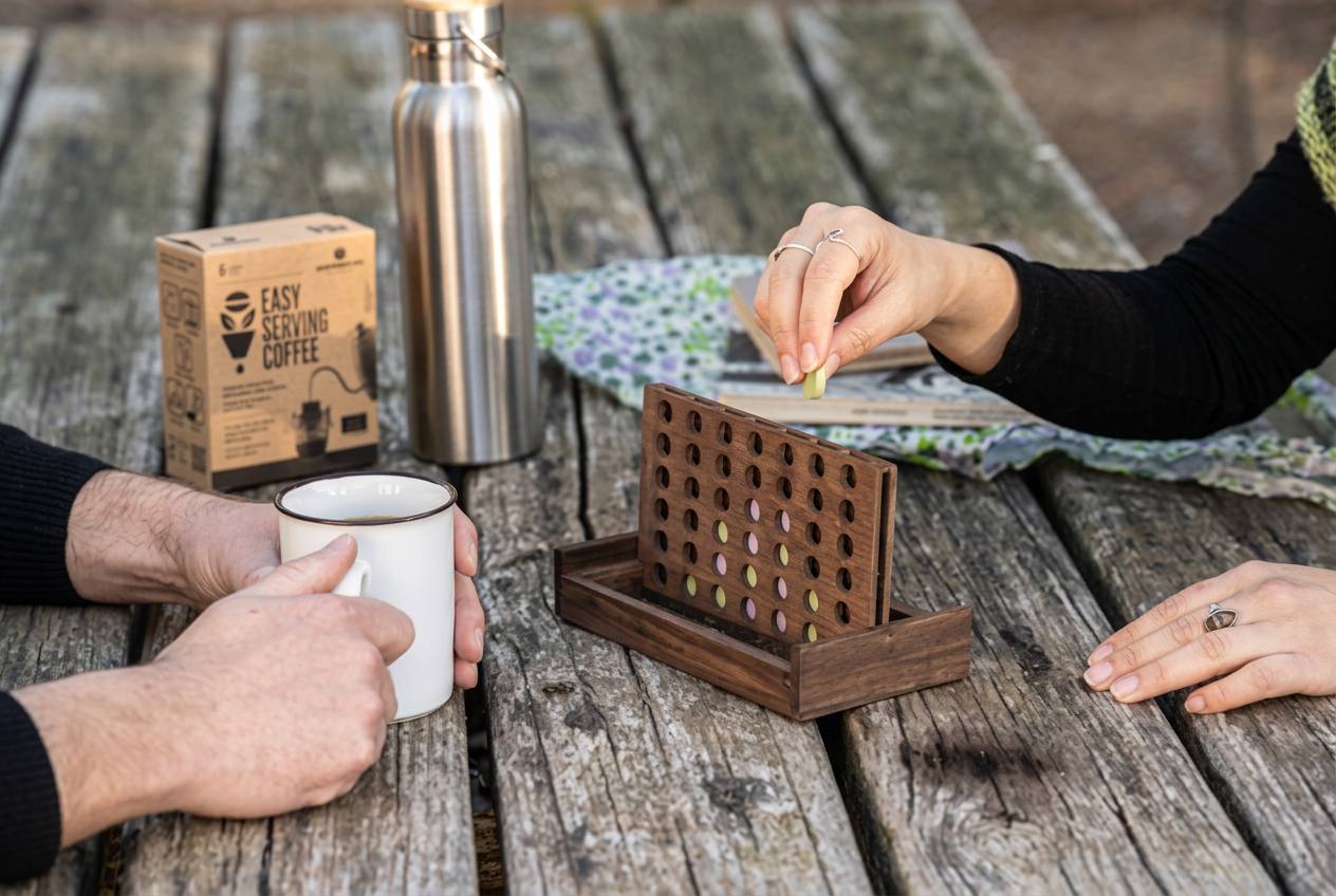Hands holding drip coffee inside a campervan by a forest lake